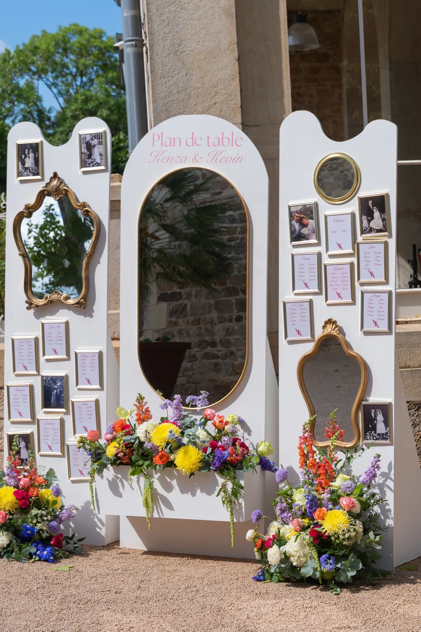 Plan de table décoratif en panneaux blancs, miroirs anciens et cadres photo, souligné de compositions florales colorées